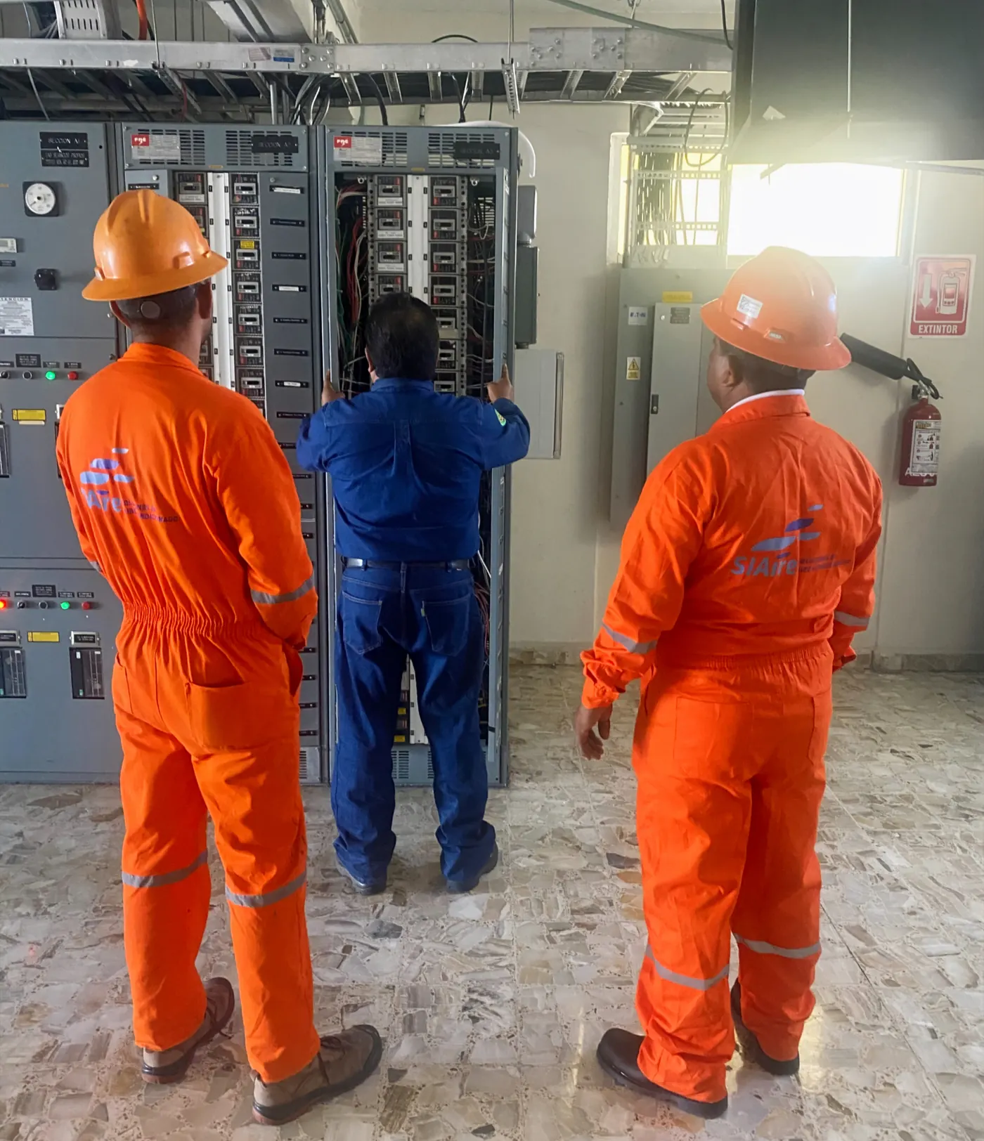 Técnicos de SIAire revisando tablero eléctrico en planta